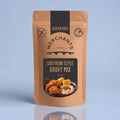 A stand-up pouch of Merchants Southern Style Gravy Mix, 150g, on a light blue background with a soft reflection below. The packaging is brown kraft paper with black and beige graphics.